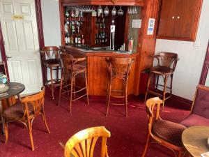 um bar com cadeiras de madeira e um balcão com garrafas de vinho em Ivydene Guest House em Skegness