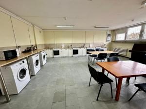 pralnia ze stołem, krzesłami i maszynami w obiekcie NARAMOWICE Hostel by Przyjazny Najem w Poznaniu