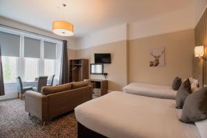 a hotel room with two beds and a couch at Embassy Apartments in Glasgow