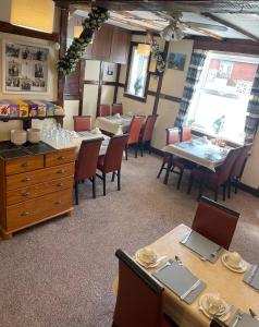 uma sala de jantar com mesas e cadeiras de madeira e tampo de mesa em Ivydene Guest House em Skegness