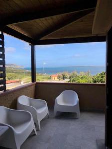 a balcony with white chairs and a view of the ocean at La Finestra sulla Torre in Stintino