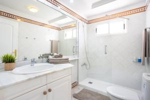 La salle de bains blanche est pourvue d'un lavabo et d'une douche. dans l'établissement EDEN RENTALS Hermosas Vistas al Océano y Los Acantilados, à Acantilado de los Gigantes
