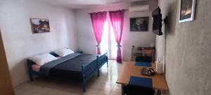 a bedroom with a bed and a window with pink curtains at STUDIO APARTMANI KIKI in Srima