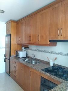 a kitchen with wooden cabinets and a sink and a refrigerator at MARIANS in Salobreña