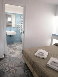 ein Schlafzimmer mit einem Bett und ein Badezimmer mit einem Waschbecken in der Unterkunft Locanda B&B Dandana in Orgosolo