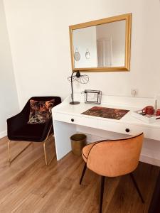 a white desk with a mirror and a chair at La Maison de Louisette in Le Faouët