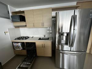 a kitchen with a stainless steel refrigerator and wooden cabinets at Apartamento con vista a Medellín in Medellín