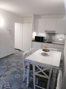 a white kitchen with a white table and chairs at Locanda B&B Dandana in Orgosolo