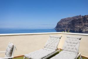 - deux chaises assises sur un balcon donnant sur l'océan dans l'établissement EDEN RENTALS Fabulosas Vistas al Mar y Los Acantilados, à Acantilado de los Gigantes