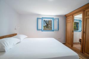 a bedroom with a white bed and a window at Kolimpithres beach house in Naousa