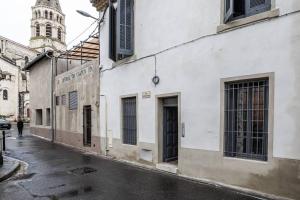 uma rua vazia com um edifício e uma torre de relógio em hawaï/parking/wifi/centre ville em Nîmes