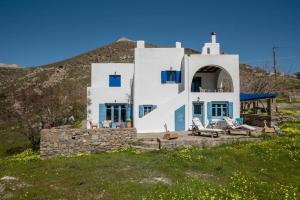 a white house with blue doors and chairs on a hill at Kolimpithres beach house in Naousa