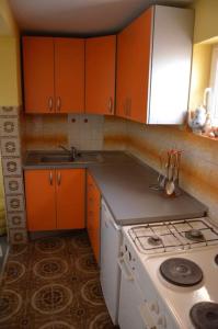 a kitchen with orange cabinets and a white stove at House with the ecogarden at the end of the Village in Čitluk