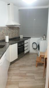 a kitchen with white cabinets and a stove top oven at Japan Beach Parque del Oeste in Málaga