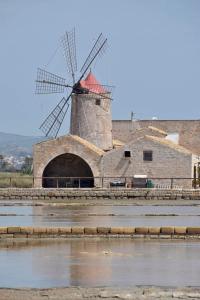 a windmill sitting next to a body of water at tropical loft in Salemi