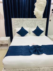 a white bed with blue pillows and a blue bow tie at SR Apartments Milimani, Kisumu in Kisumu