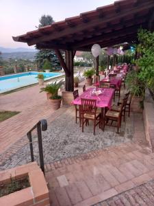 ein Restaurant mit rosa Tischen und Stühlen neben einem Pool in der Unterkunft Agriturismo Borgo Nuovo Sant'Agata dei Goti in Migliara