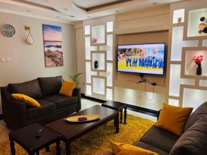sala de estar con sofá y TV en la pared en SR Apartments Milimani, Kisumu, en Kisumu