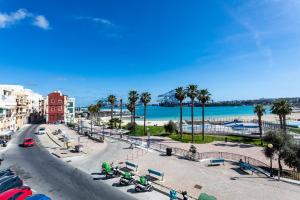 una strada cittadina con palme e una spiaggia di Gospa 58 - 1 bedroom apt a Birżebbuġa