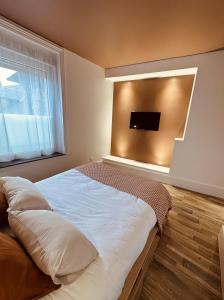 - une chambre avec un lit et une télévision murale dans l'établissement Studio 2 du SPA Célinie, à Warcq