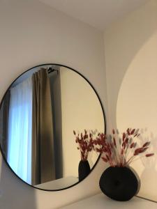 a mirror on a wall with a vase with flowers at Latea luxury apartment in Lukavica