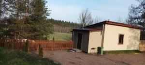 a small building with a fence next to a field at Domek Zielenina in Mierzeszyn