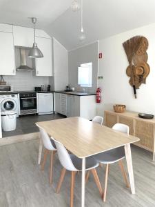 a kitchen with a wooden table and white chairs at Casa da Tia in Sesimbra