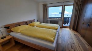 1 dormitorio con 1 cama con sábanas amarillas y ventana en Apartment Kirchmair en Innsbruck