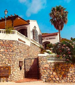 um edifício de pedra com uma palmeira em frente em La Ventera - summer hotel em Gualchos