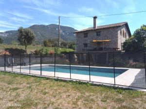 a fence around a swimming pool in front of a house at Allotjatments Can Servosa in Sales del Llierca