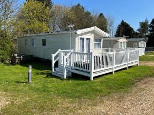 a small white house with a porch and a deck at Luxury 3 Bedroom Caravan MC37, Shanklin, Isle of Wight in Shanklin