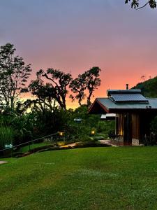 a house with a green lawn in front of a sunset at Hotel de Montaña El Pelicano in San Isidro