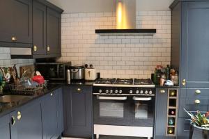a kitchen with black cabinets and a stove top oven at Beautiful maisonnette flat in Islington in London