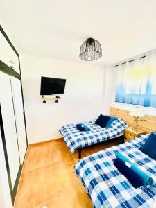 a room with two beds and a tv on the wall at Apartament Bella Vista in Los Nietos