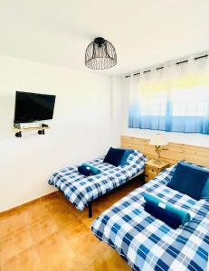 two beds in a room with a tv on the wall at Apartament Bella Vista in Los Nietos