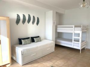 um quarto com uma cama branca e beliches em A Casa Dos Amigos em Sesimbra