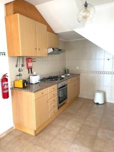 a kitchen with wooden cabinets and a stove top oven at A Casa Dos Amigos in Sesimbra