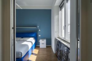 a bedroom with a bed with blue walls and a window at Easylife - Accogliente appartamento in Bocconi in Milan