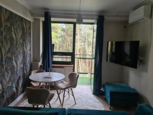 ein Wohnzimmer mit einem Tisch und einem Fenster in der Unterkunft Apartament Zegrzyński z widokiem in Serock