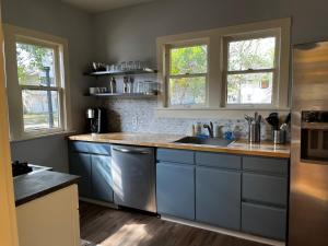 a kitchen with blue cabinets and a sink and two windows at Southern Charm in Lakeland in Lakeland