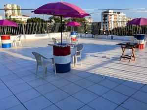 un patio con mesas, sillas y sombrillas púrpuras en Ozama Studios, en Santo Domingo