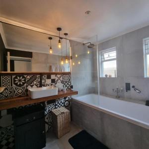 een badkamer met een bad, een wastafel en een spiegel bij Kwikstertjie in Hermanus