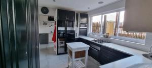 uma cozinha com armários pretos e um balcão branco em Kwikstertjie em Hermanus