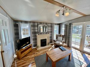 a living room with a tv and a fireplace at Leaf Lane Lodge in Newton on the Moor