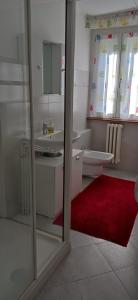 a bathroom with a toilet and a red rug at CASA MICHELA BB OSSOLA PARKING FREE in Domodossola