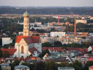 a church with a clock tower on top of a city at Royal - Sky - Suite in Augsburg