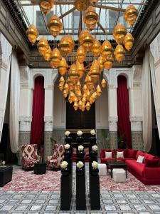 un soggiorno con un grande lampadario a braccio e mobili rossi di Palais De Fès Suites & Spa a Fes