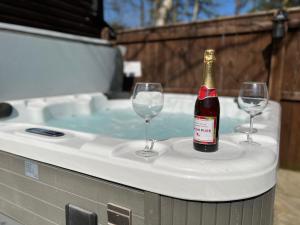 a bottle of wine and two wine glasses on a hot tub at Eagle Lodge in Newton on the Moor