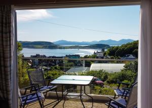 a balcony with a table and chairs and a view of the water at Benvoulin Bothy - luxury pod with stunning views in Oban
