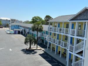 a row of buildings with palm trees in a parking lot at Pirates Cove in Carolina Beach